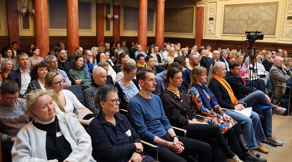 Ein Saal voller Menschen, die in mehreren Reihen auf Stühlen sitzen.