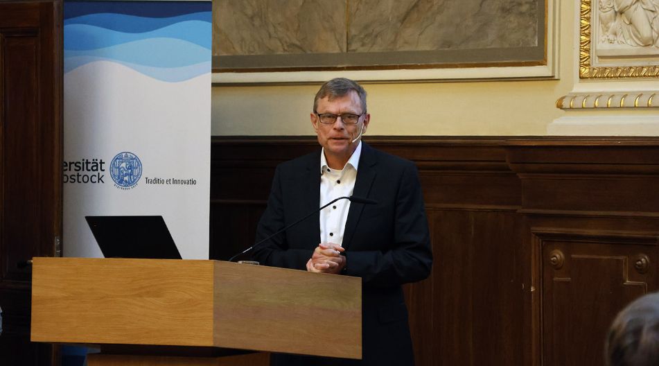 Ein Mann hält an einem Podium einen Vortrag.