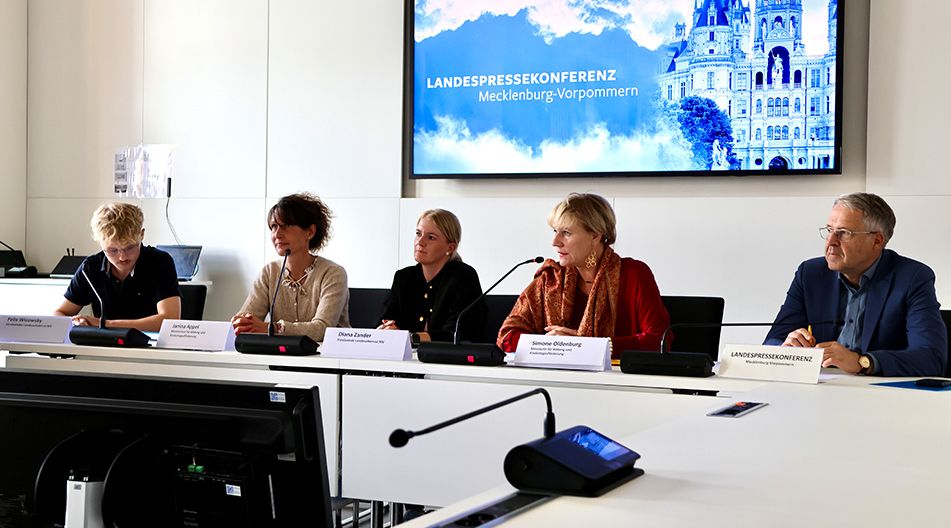 Fünf Personen sitzen bei der Landespressekonferenz in Mecklenburg-Vorpommern an einem Tisch mit Mikrofonen vor einer Präsentationswand.